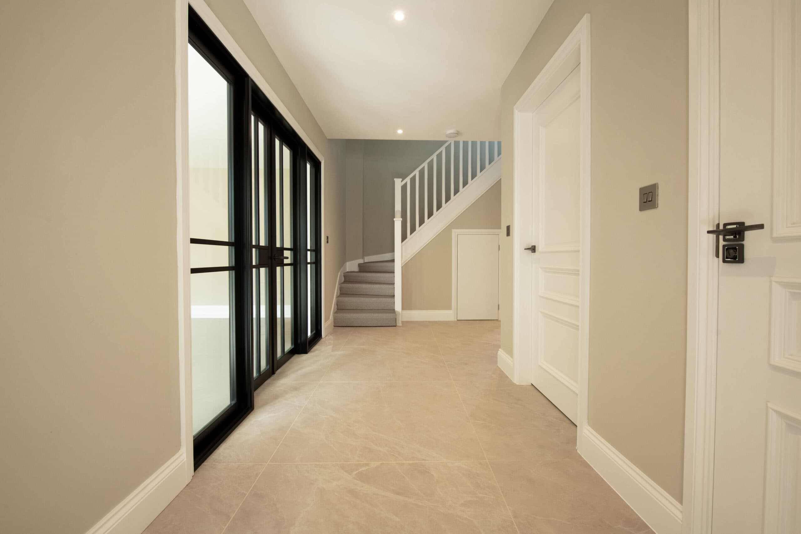 Bright hallway with black-framed glazed doors and a white staircase